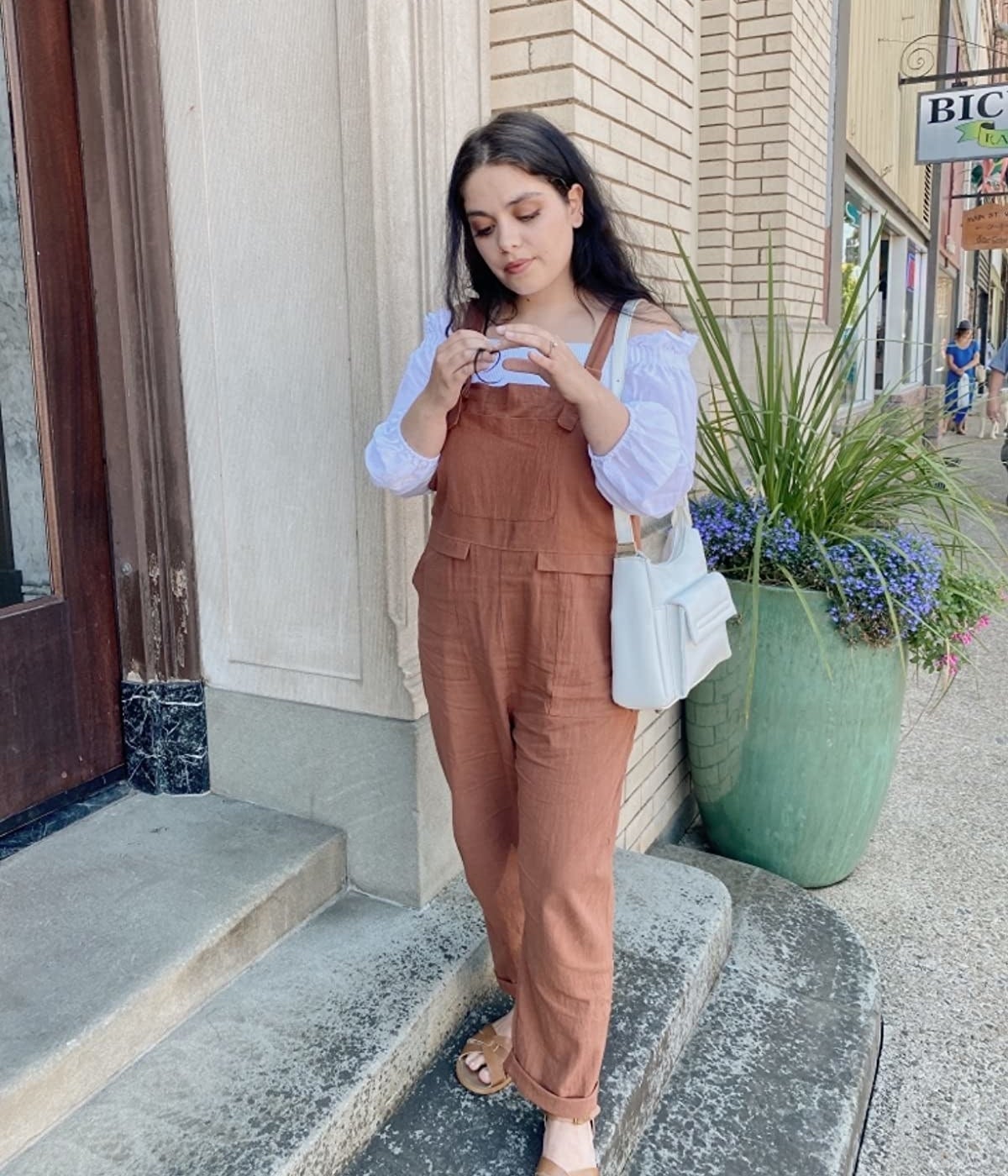 reviewer outdoors wearing the brown overalls in size small