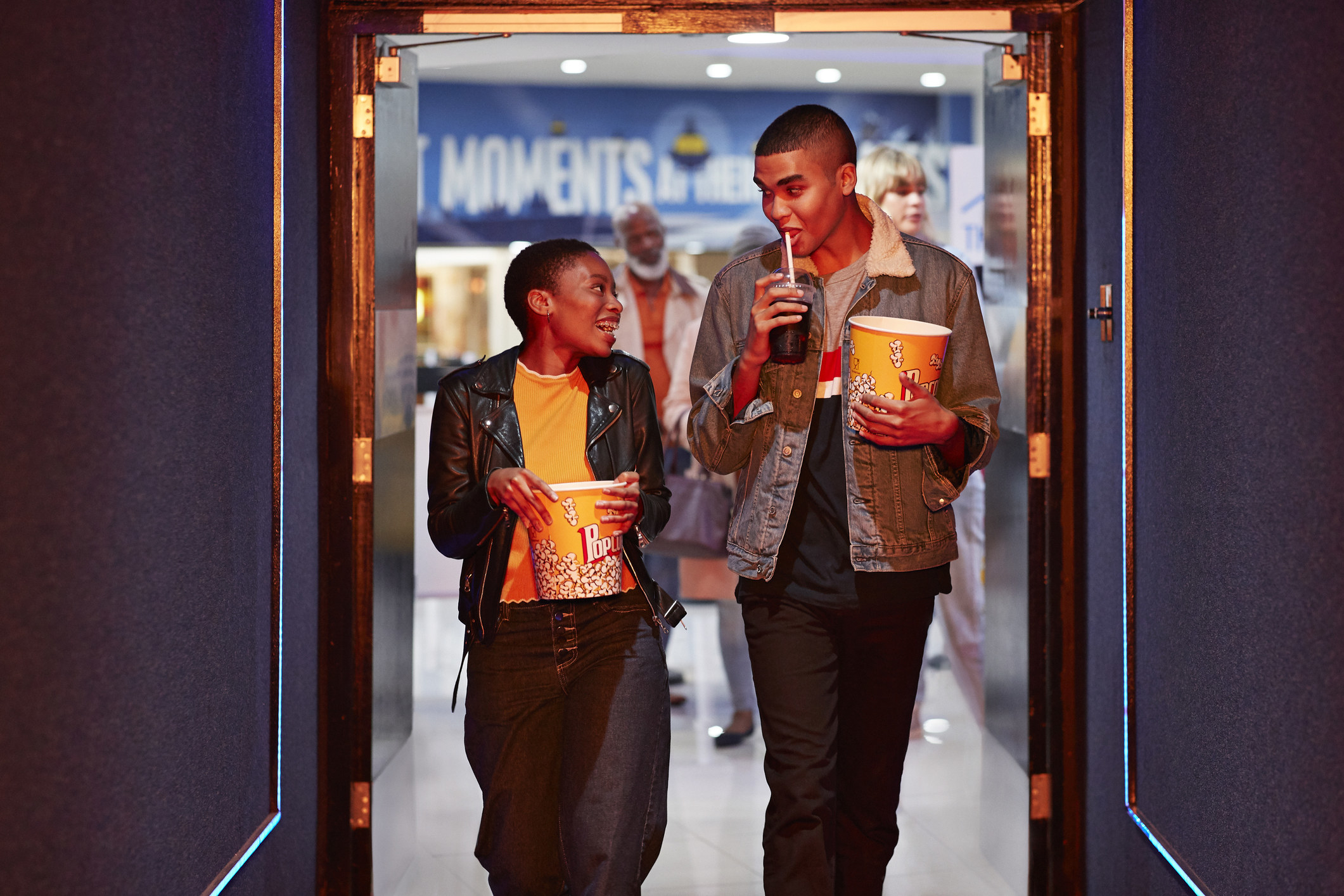 A couple talking while walking in corridor, exiting a movie date.