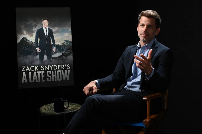 Zack Snyder sits in front of a poster