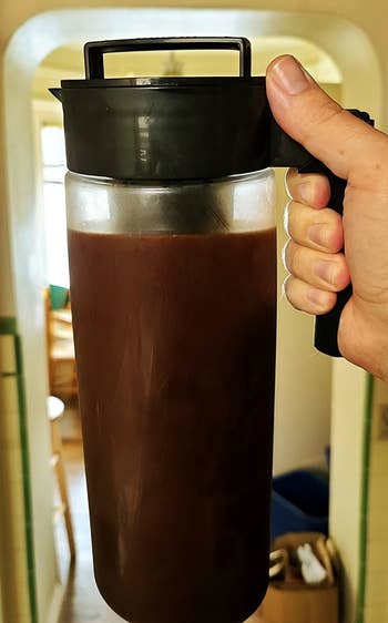 a reviewer holding a carafe of cold brew coffee