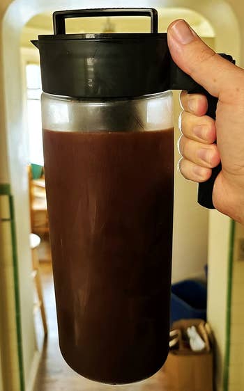 a reviewer photo of a hand holding a carafe of cold brew coffee