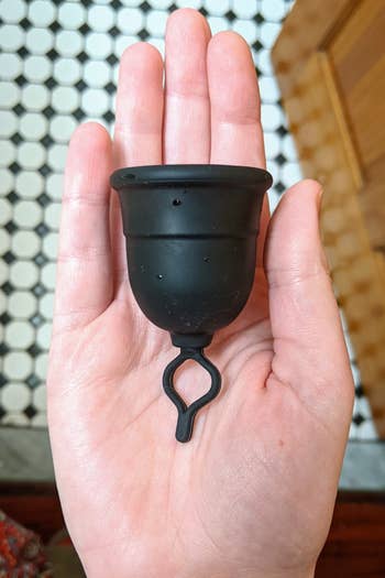 a BuzzFeed writer holding the menstrual cup