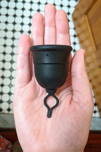 a BuzzFeed writer holding the menstrual cup