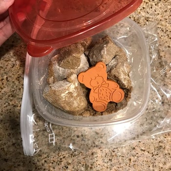 a reviewer photo of the sugar bear inside a container filled with hard clumps of brown sugar