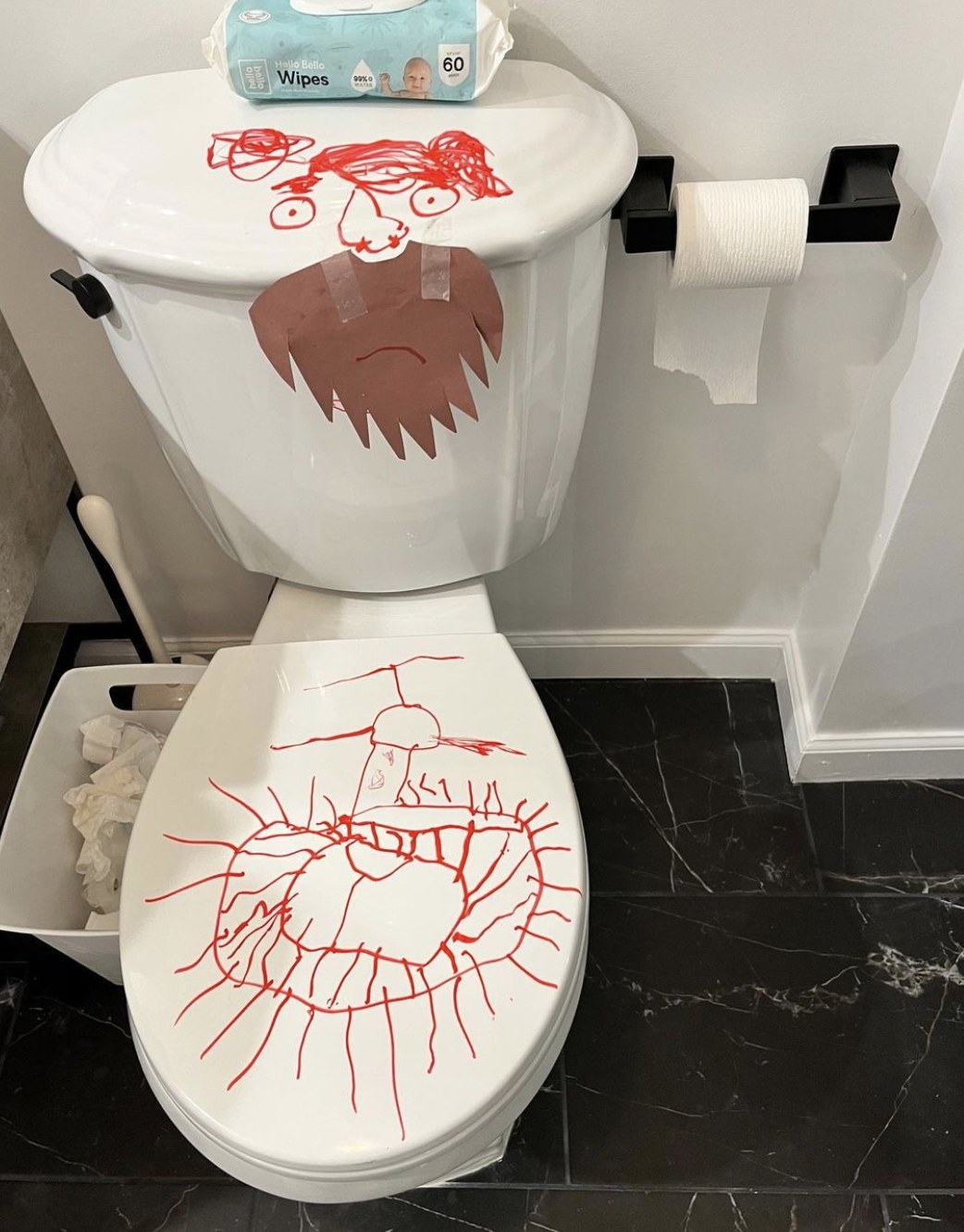 A toilet with a red face drawn on the top and scribbles on the seat