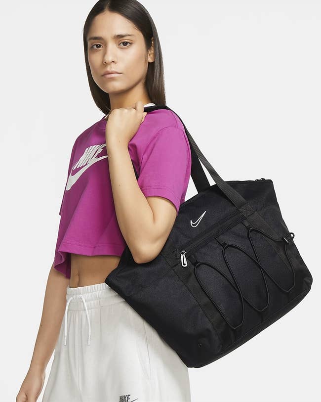 Model wearing black tote, pink cropped tee and white sweatpants
