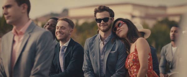 Jack Quaid as Ben looks at couple getting married as Alice, played by Maya Eskrine, rests her head on his shoulder