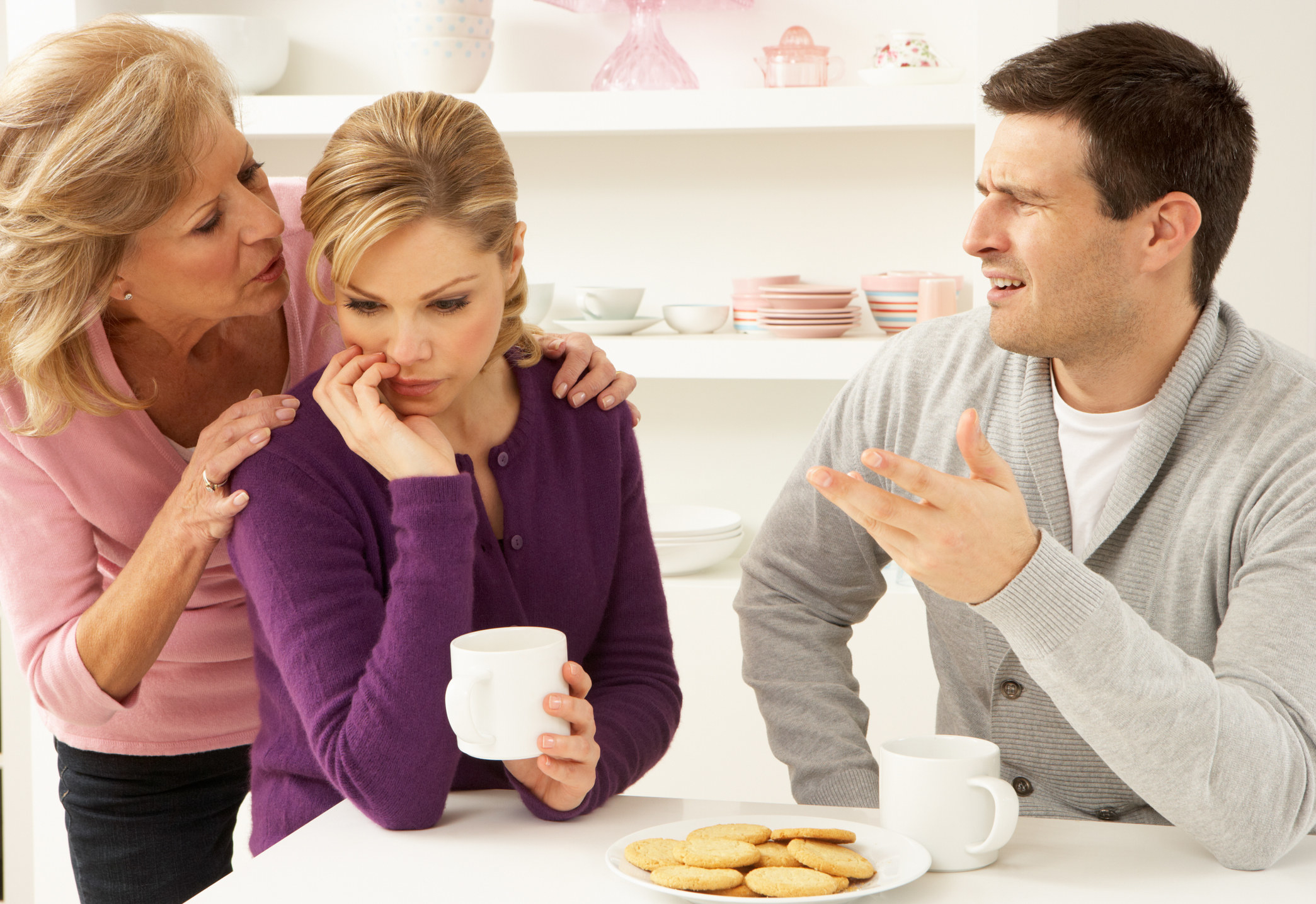 Senior mother interfering with couple having argument at home sitting at table