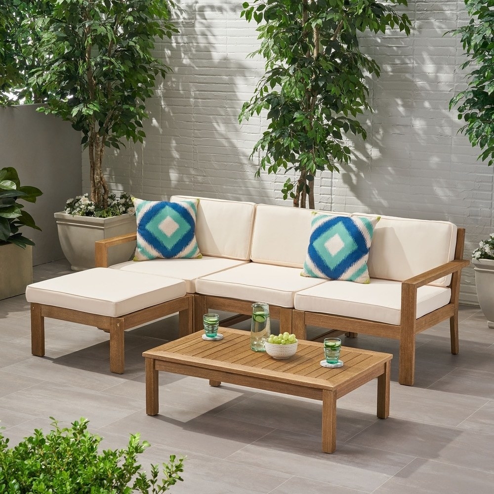 three-seater wooden sectional with cream-colored cushions in a shaded patio