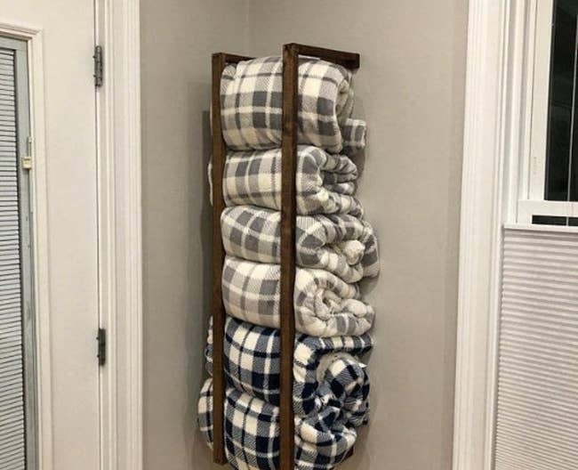 a wall-mounted blanket rack filled with six throw blanket