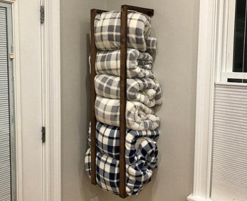 a wall-mounted blanket rack filled with six throw blanket