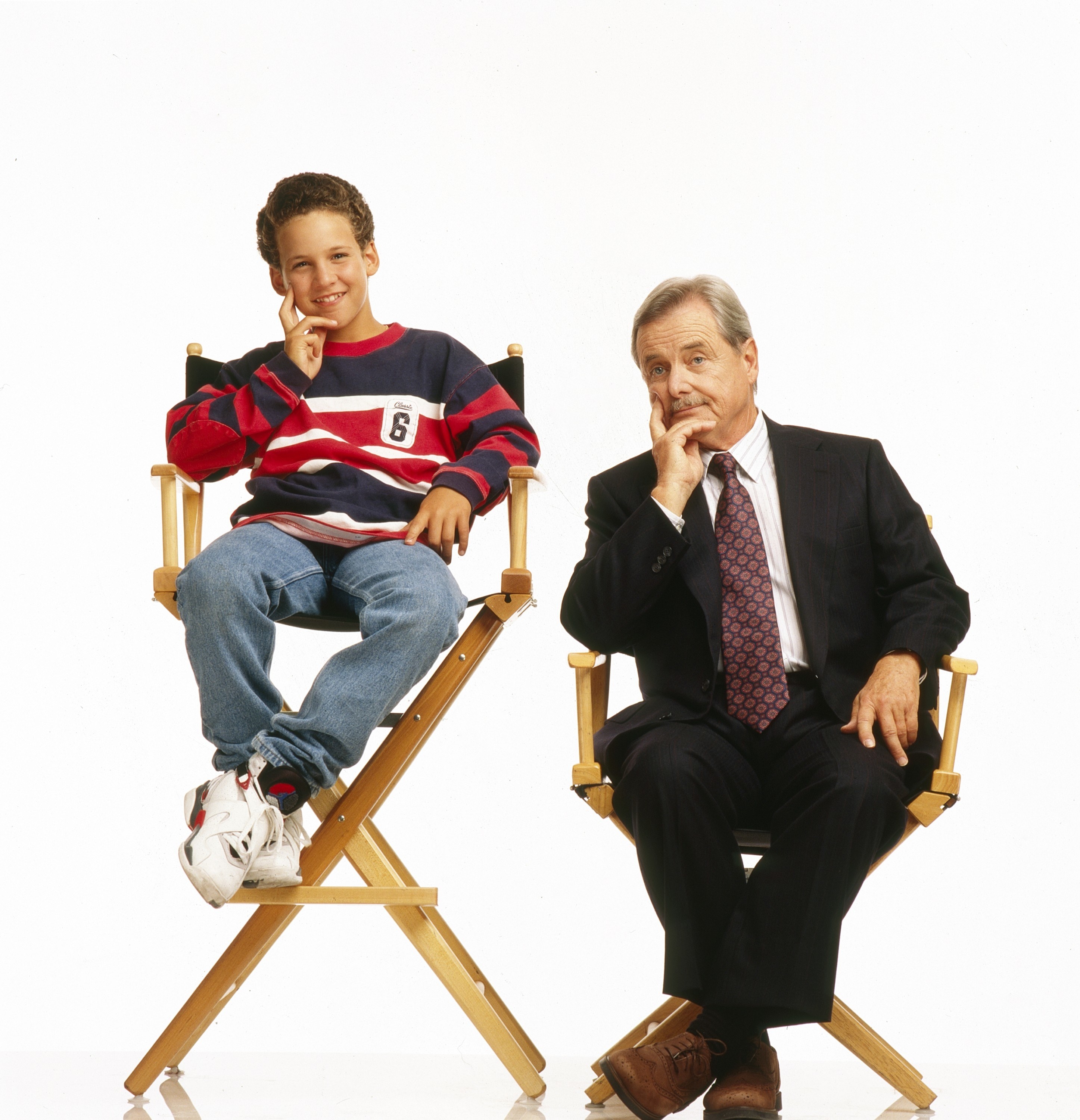 Mr. Feeny sitting in a director&#x27;s chair that&#x27;s a lot shorter than the chair that a very young Cory is sitting in next to him