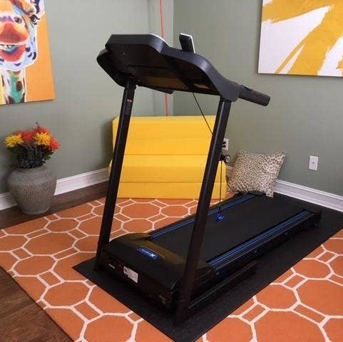 the treadmill set up in a reviewer's home with a mat underneath