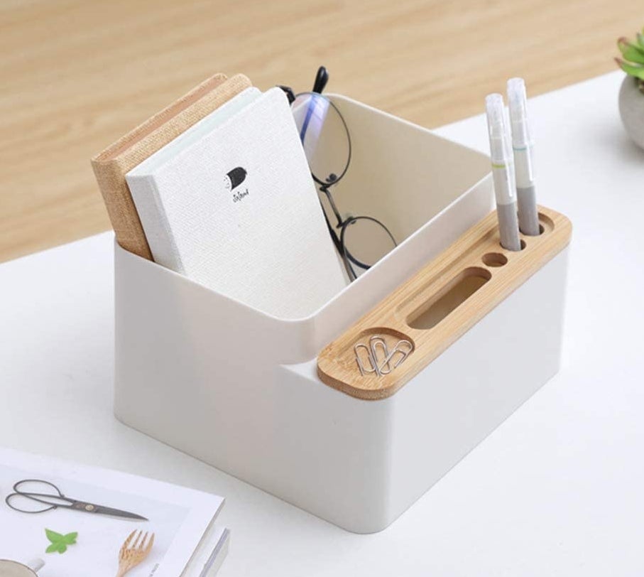 the white and wood desk organizer holding some notebooks, pens, paper clips, and a pair of glasses
