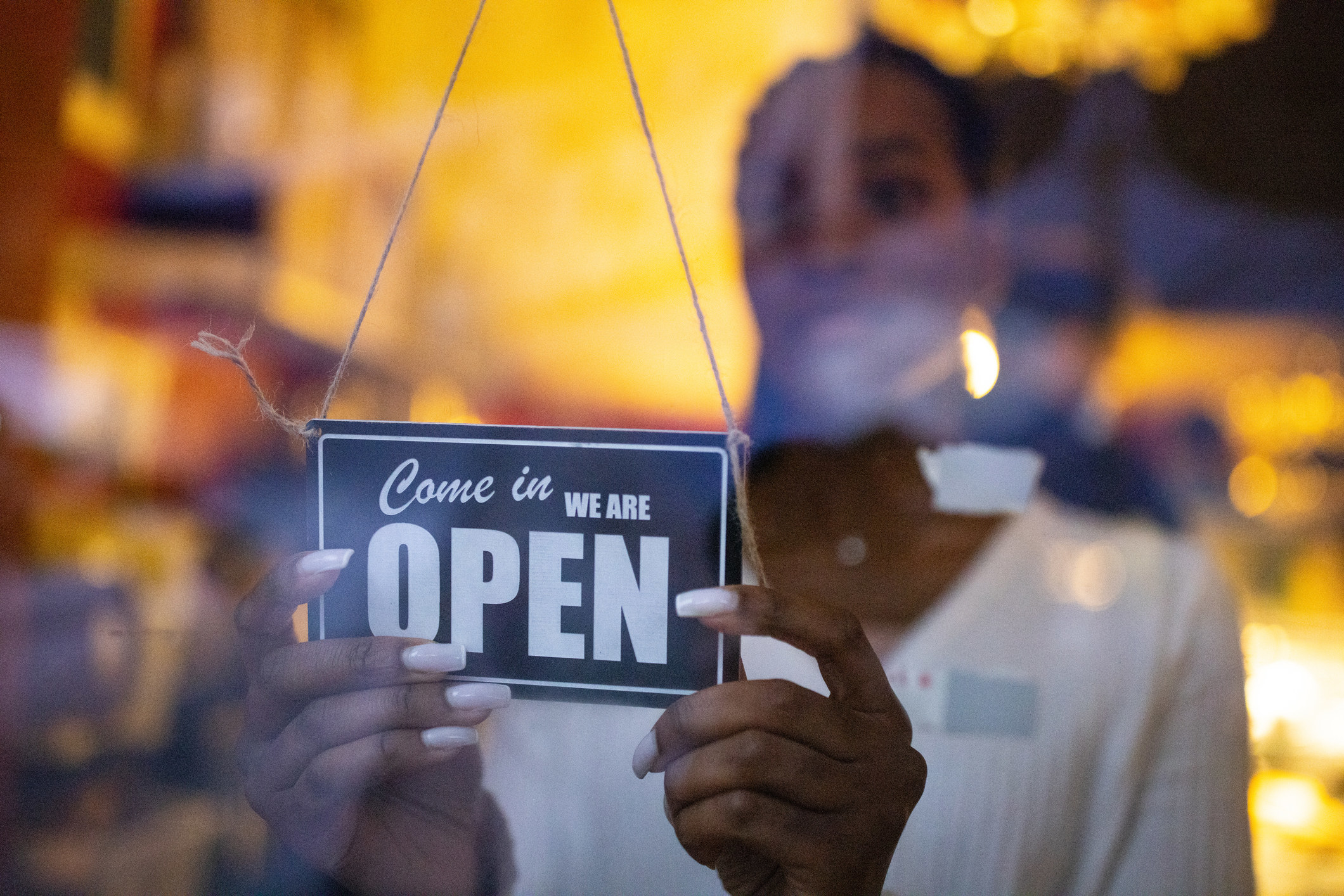 Person hanging an open sign in the window of their business