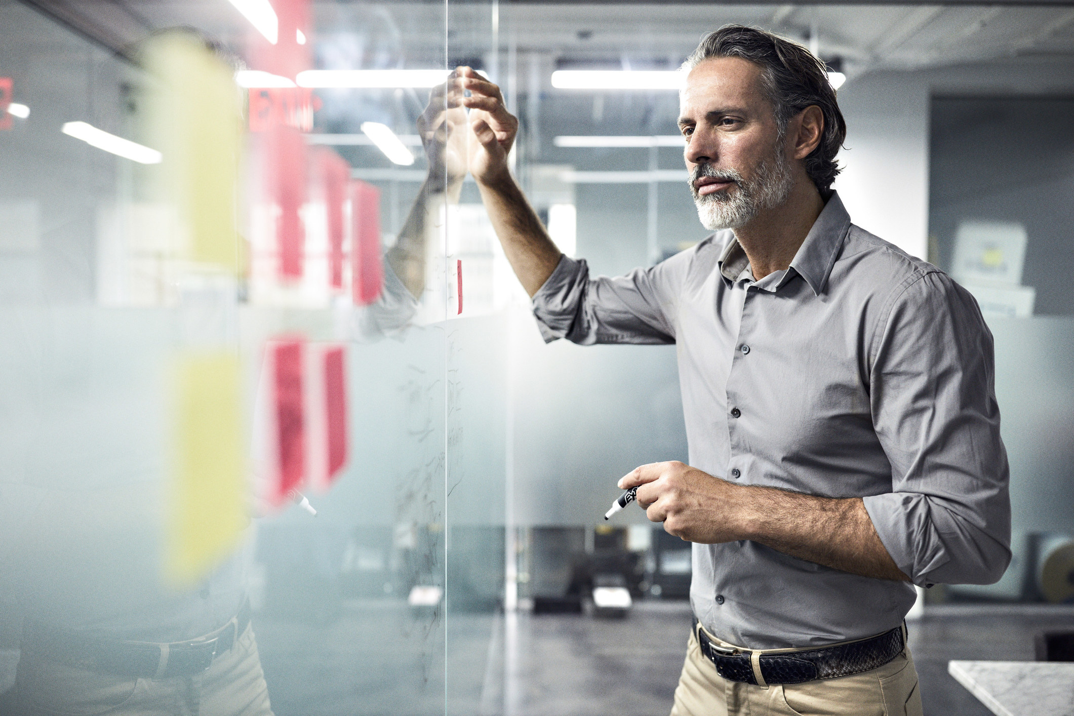 Businessperson looking at adhesive notes on window in office