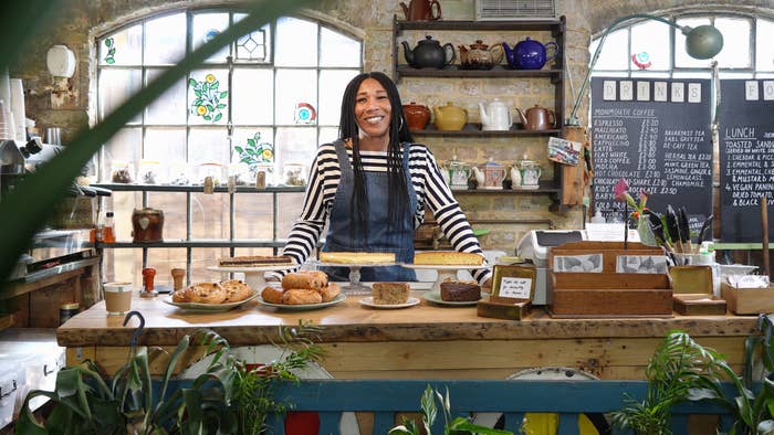 woman wearing an apron standing behind a table of baked goods