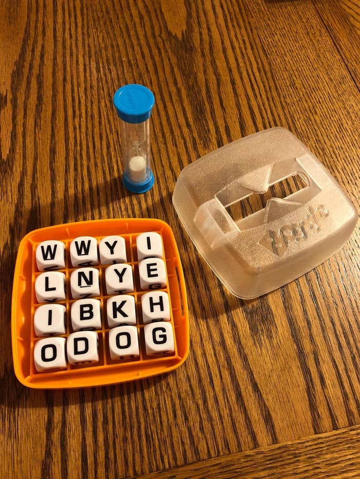 reviewer&#x27;s boggle game with the top off and the timer next to it