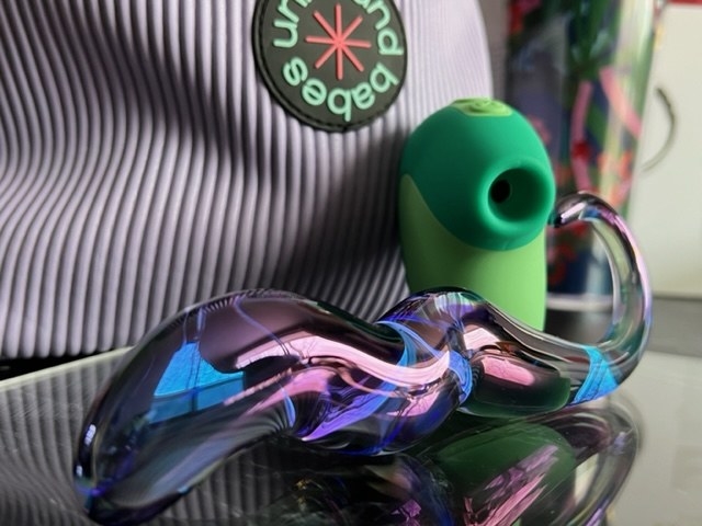 Iridescent glass dildo next to mint vibrator