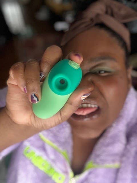 Reviewer holding mint green suction vibrator