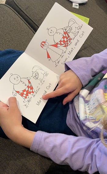reviewer's child reading a story with a human and cat illustrations