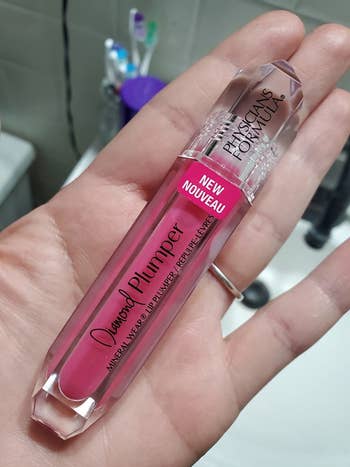 Reviewer holding pink tube of lip plumping gloss