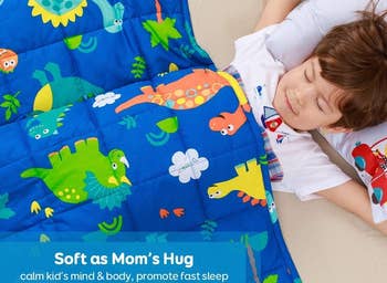 Child sleeping with the blue weighted blanket in dinosaur print