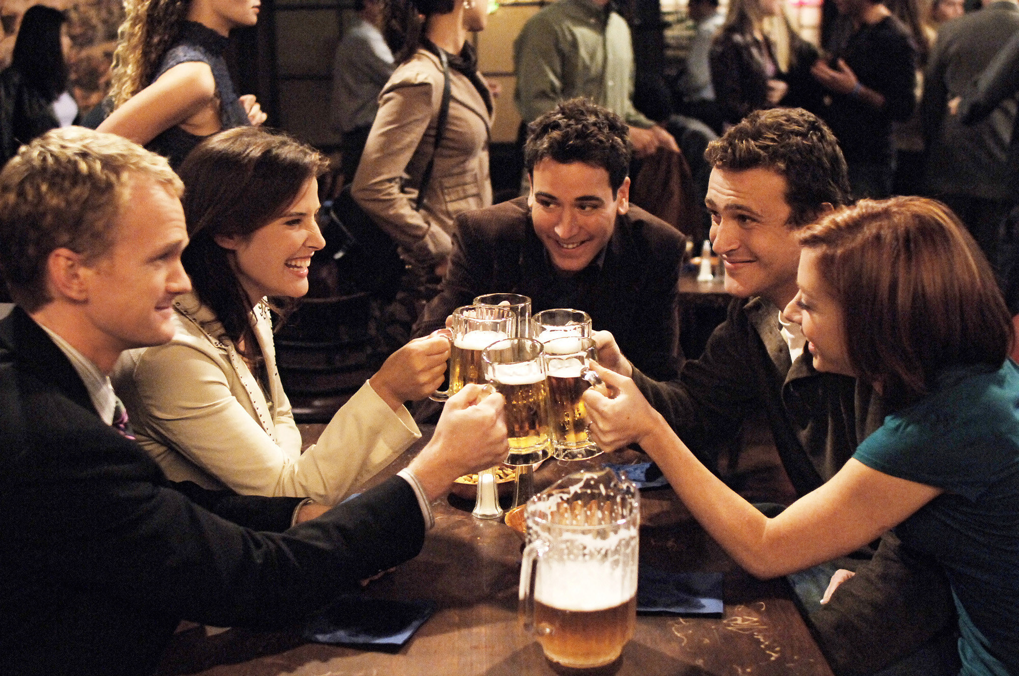 The cast of HIMYM does a group cheers with mugs of beer