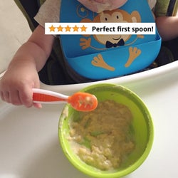reviewer's photo showing their child using the spoon to eat oatmeal from a bowl with the words 