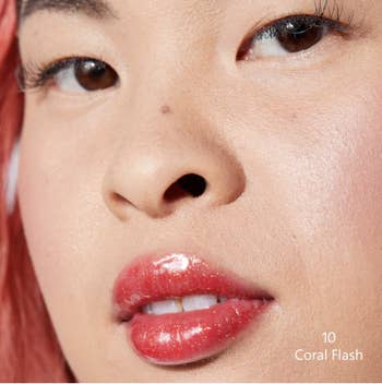 Model wearing coral lip gloss