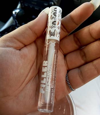 Reviewer holding clear tube of lip plumping gloss