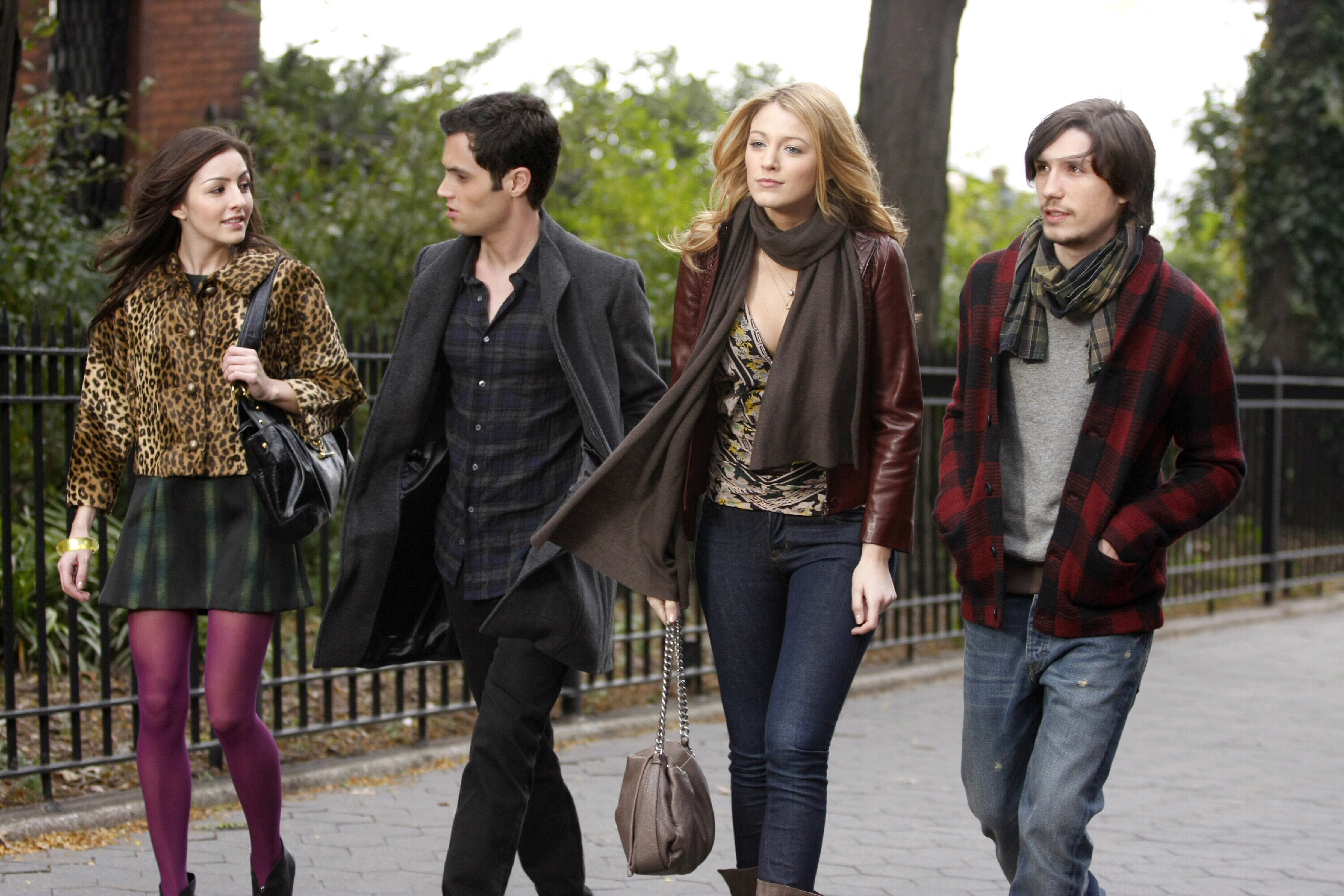 Four characters in Gossip Girl walk side-by-side in the park