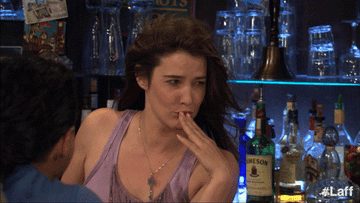 Robin from HIMYM blows a kiss from behind the bar