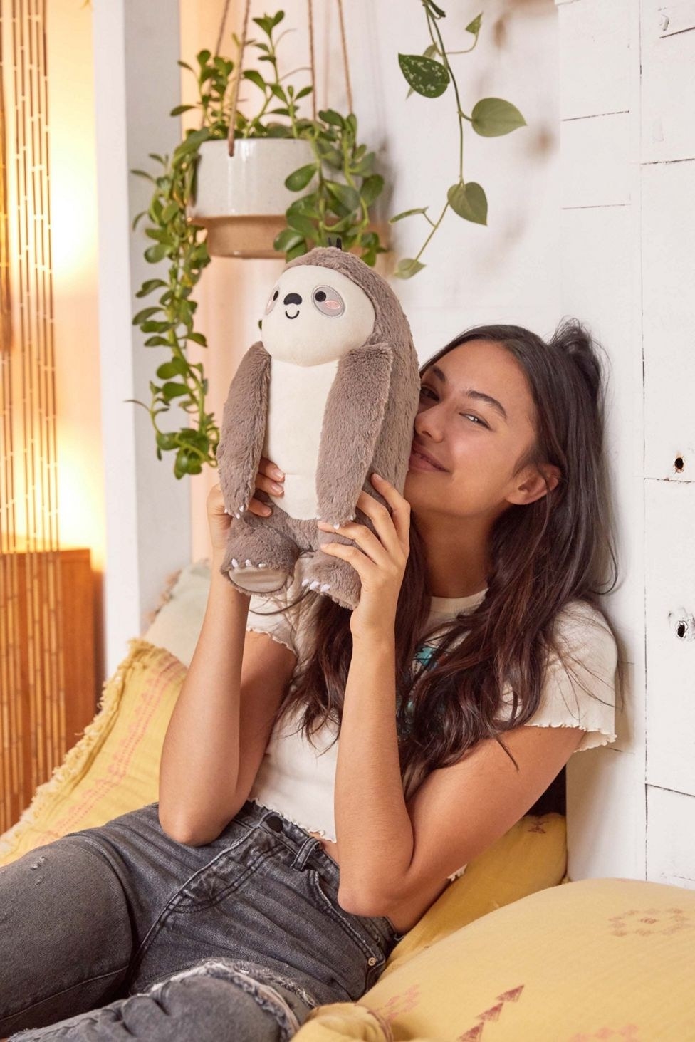 Model holding the sloth plushie