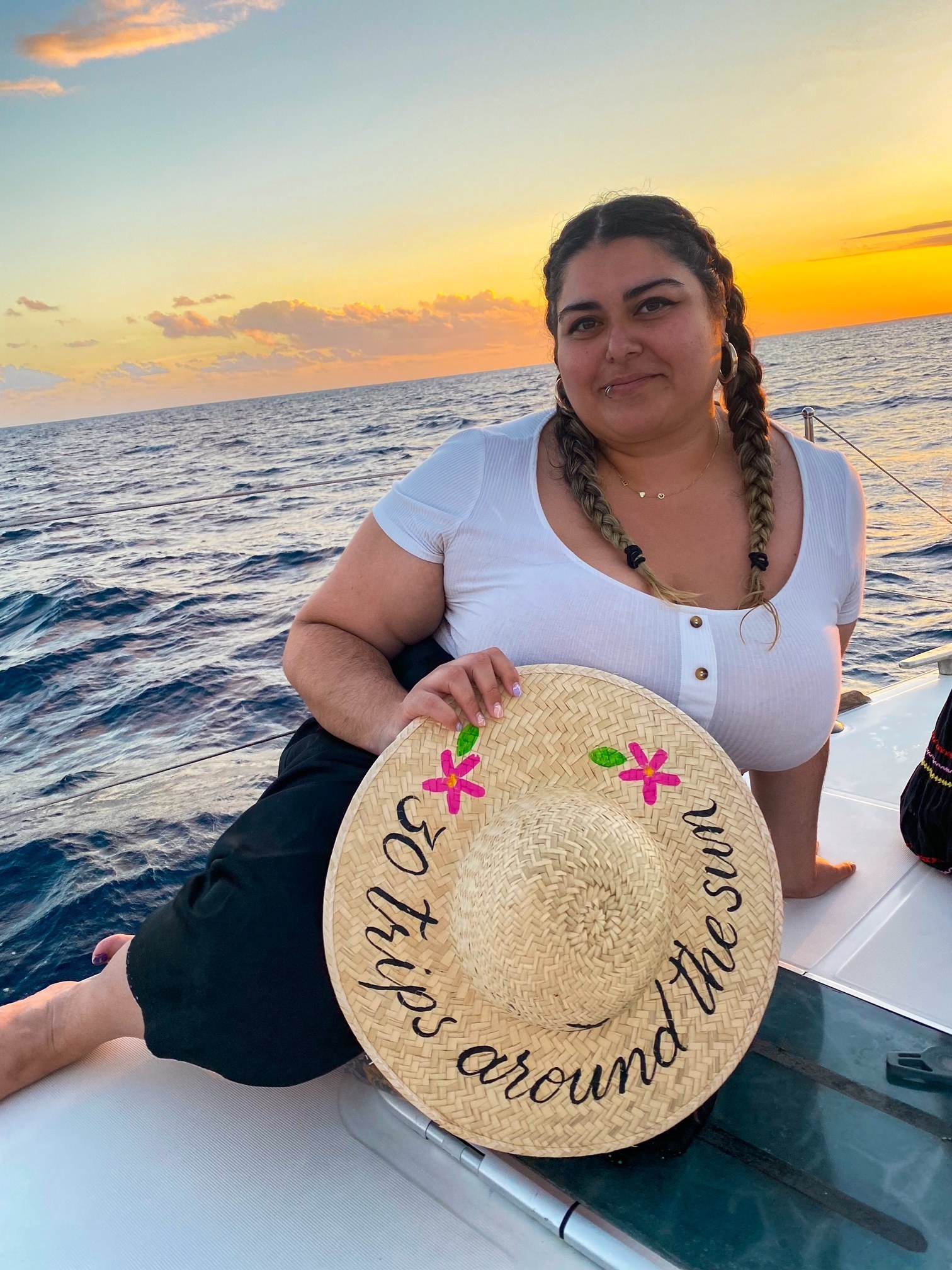 Woman on a boat holding a hat that says &quot;30 trips around the sun&quot;