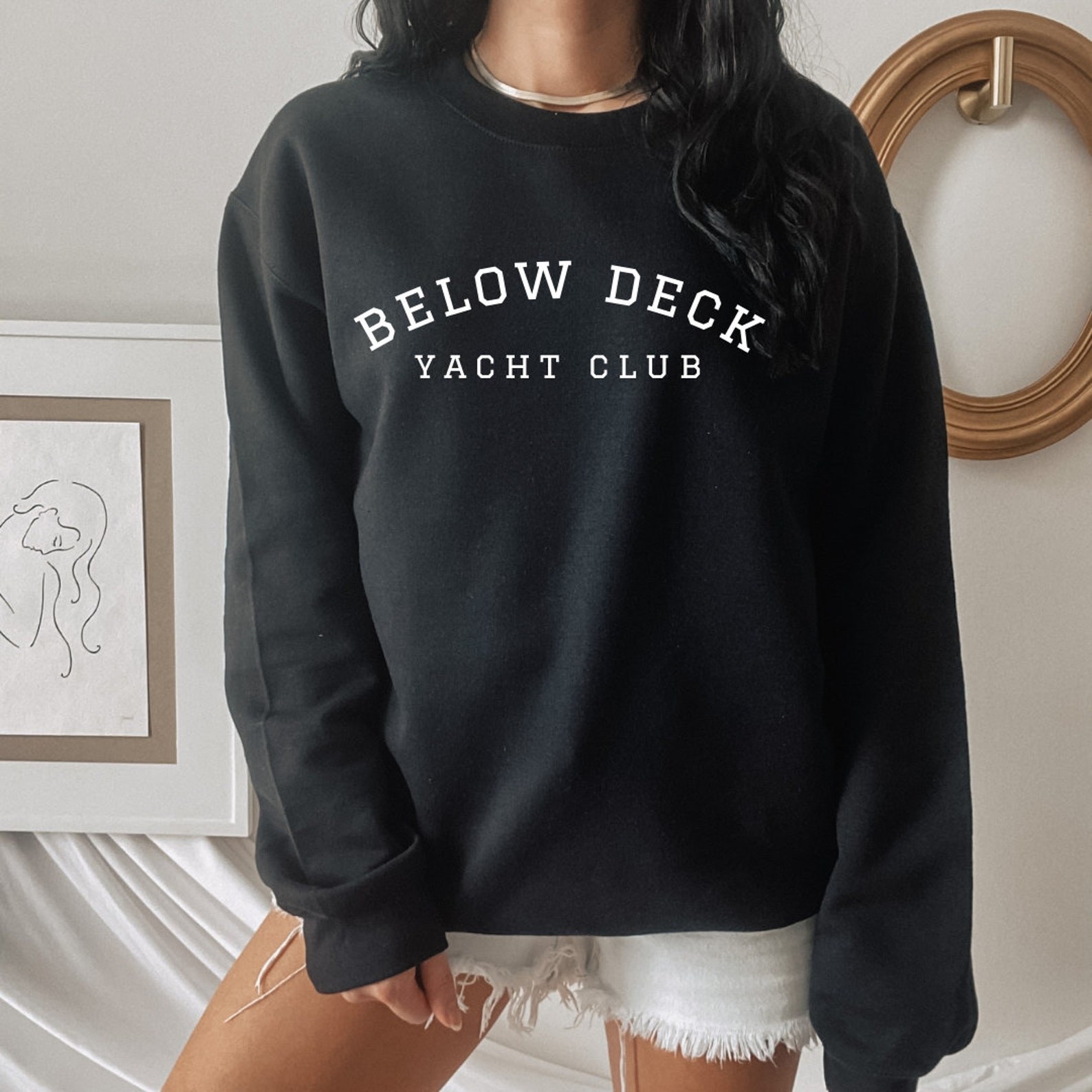 a model wearing a black crewneck sweatshirt that says &quot;below deck yacht club&quot;