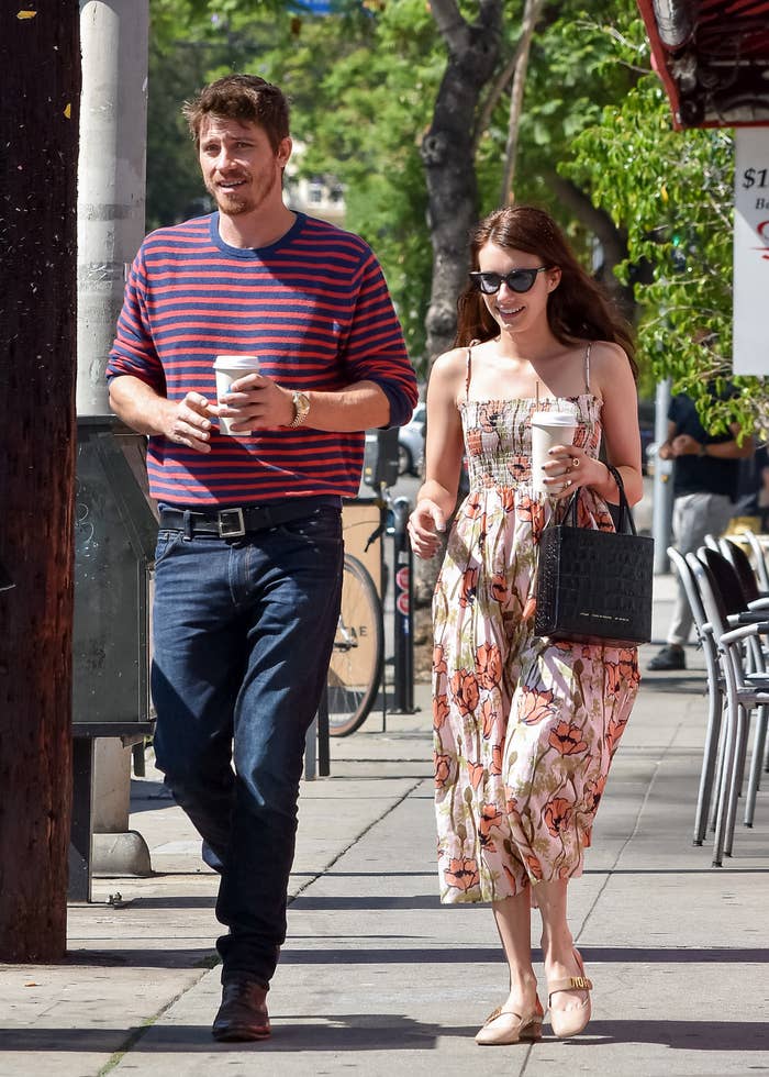 Garret and Emma walking down a sidewalk with coffee in their hands