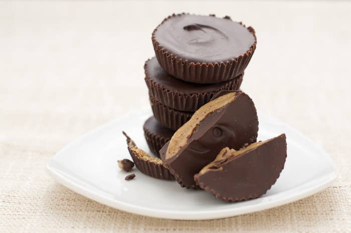 Homemade peanut butter cups stacked on a plate on a white tablecloth.