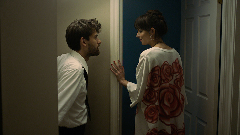 A man and woman stand in a hallway looking at each other
