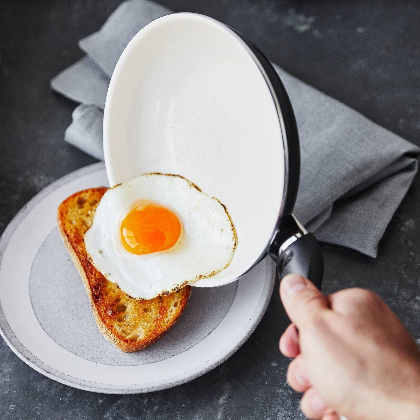 Model sliding egg on to bread from white pan