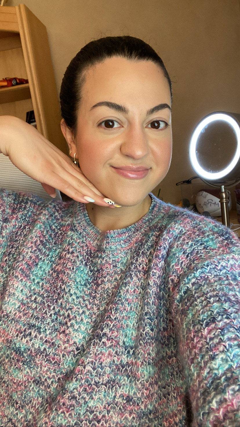 A selfie of the author wearing a sweater and her hair back showing her base makeup