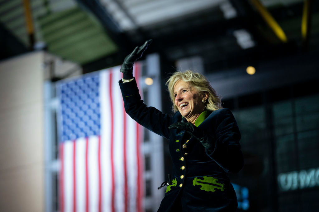 Dr. Biden waving to a crowd as she stands on a stage