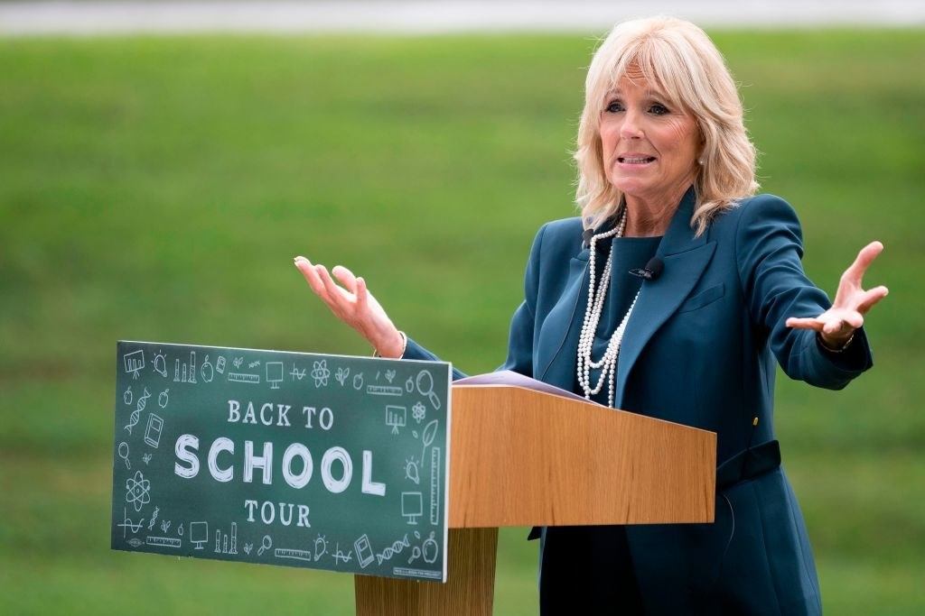 Dr. Biden speaking at a podium that says Back to School Tour with her arms outstretched 