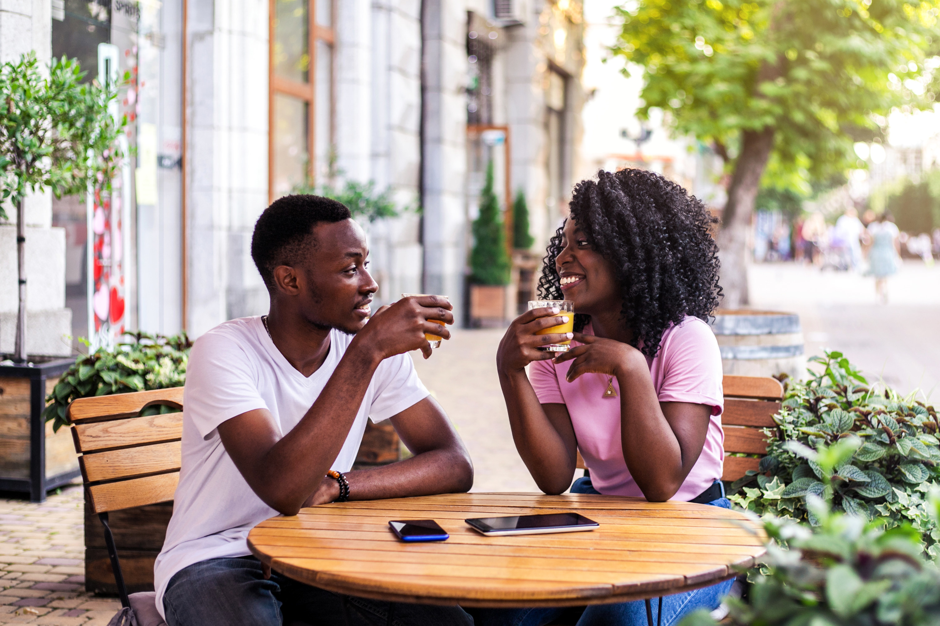 A man and a woman sitting outside at a table drinking something