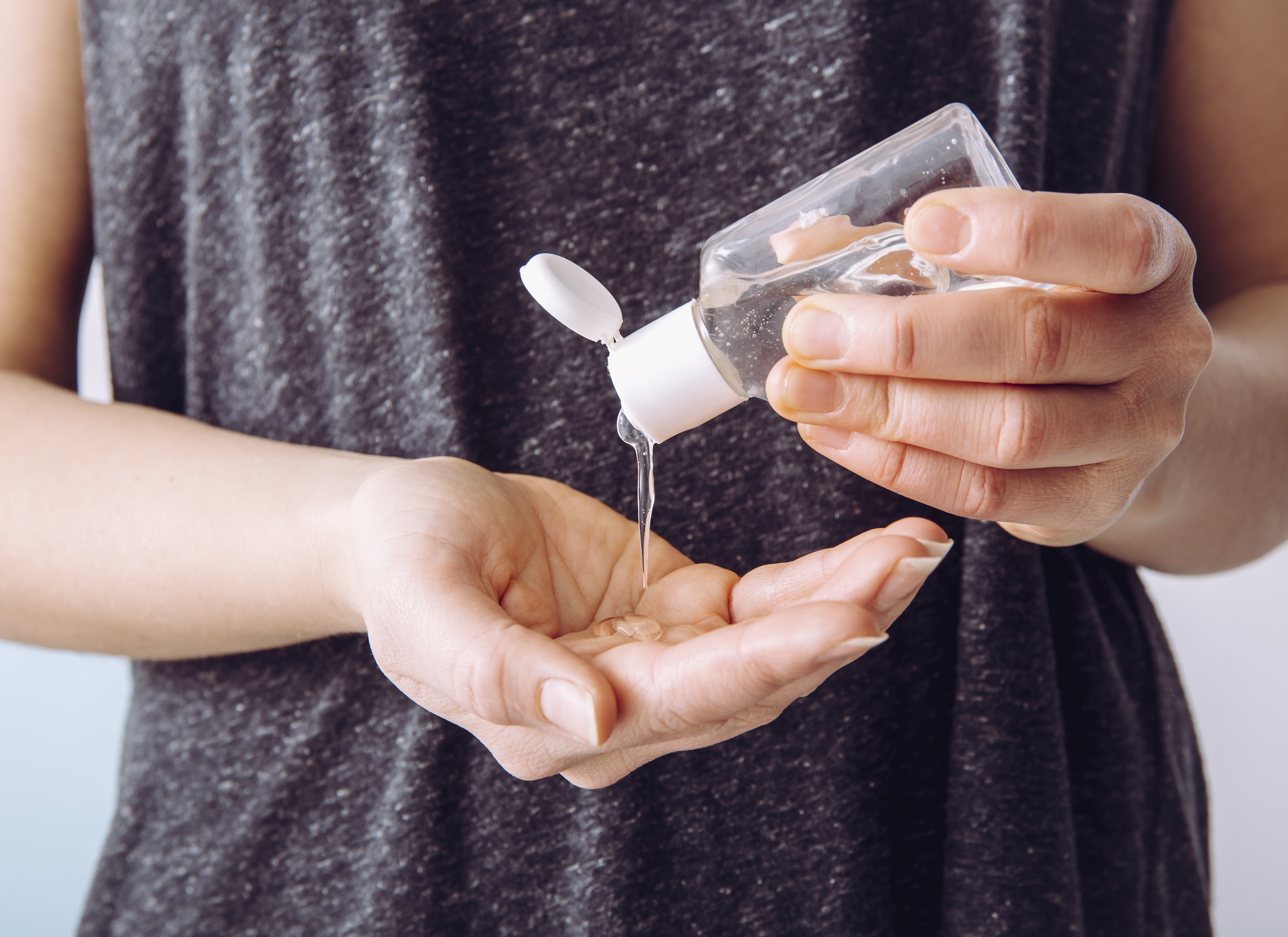 A person pouring hand sanitizer into their other hand