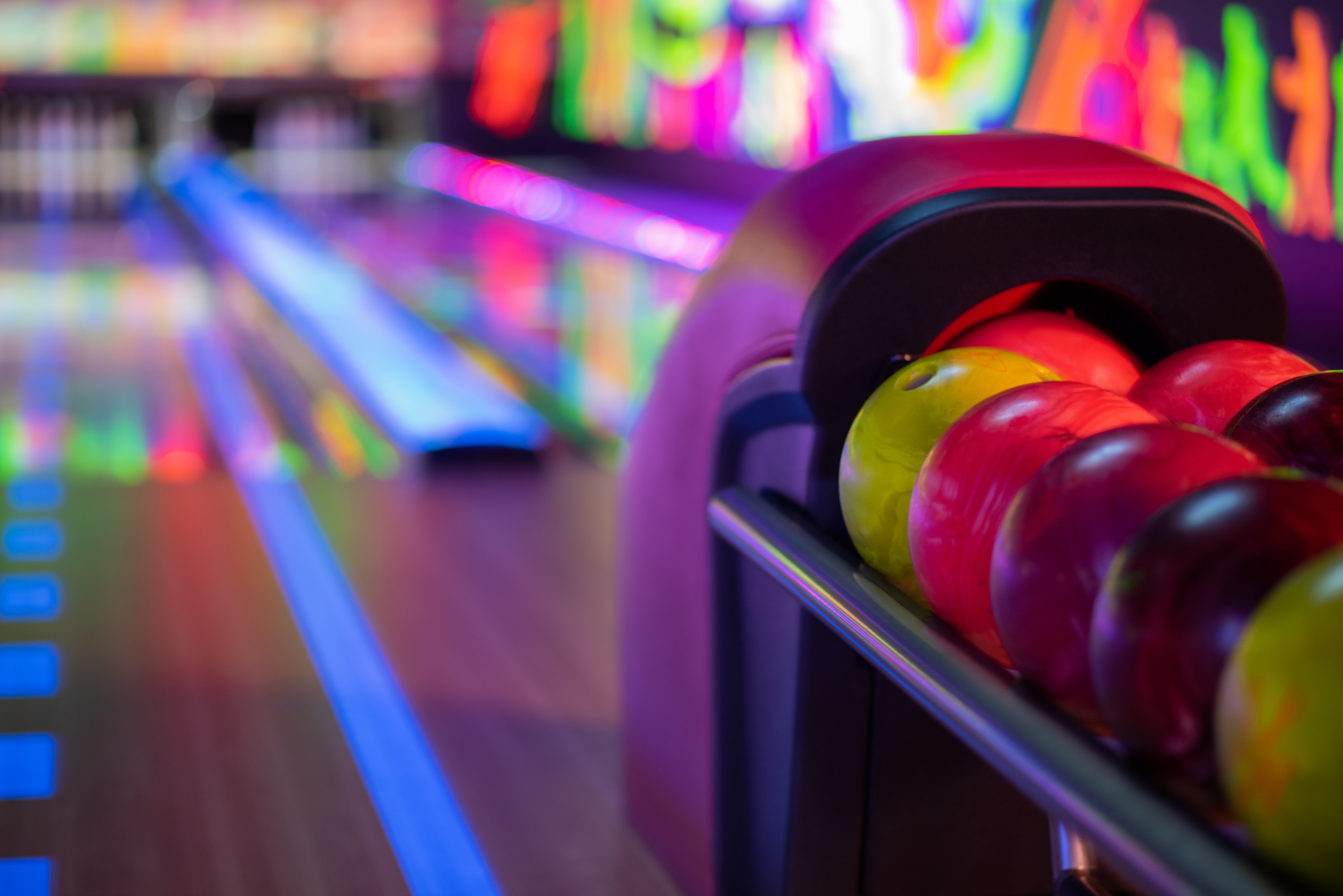 A bowling alley in the distance with a close up shot of bowling balls.