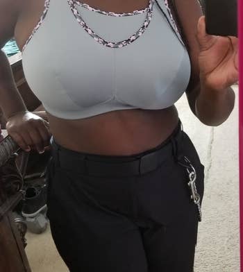 reviewer with a larger bust wearing the gray version of the bra which has a neckline that comes up well above where cleavage will begin