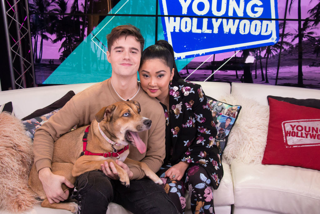 The couple holding a large dog as they sit on a couch during a Young Hollywood event