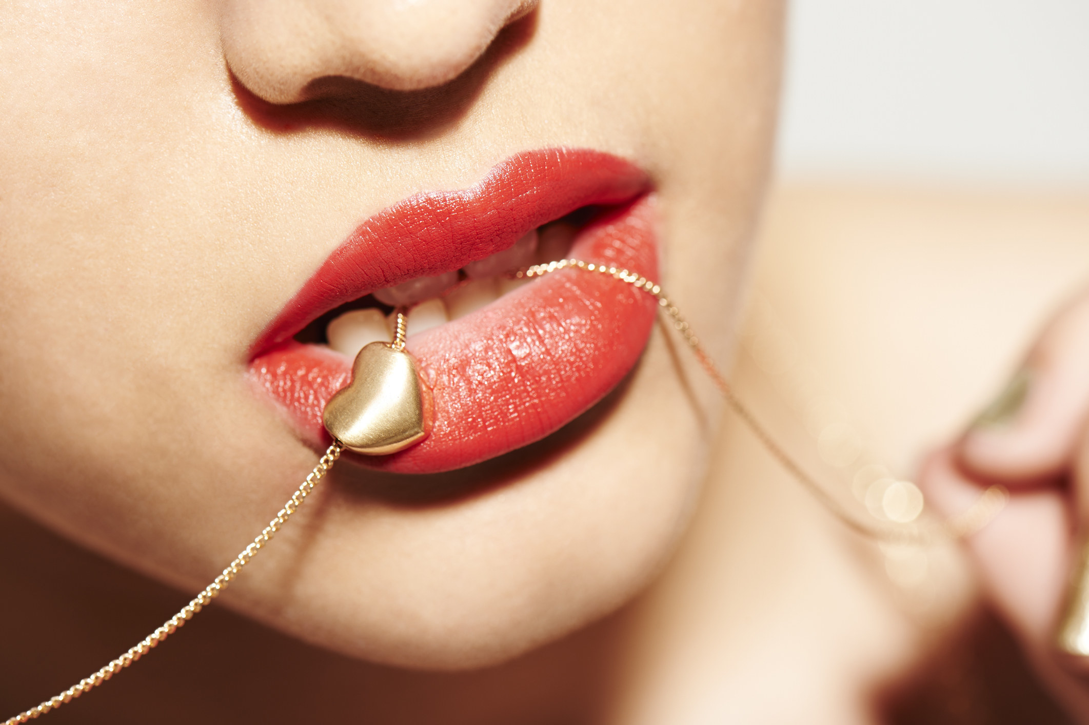 Woman holding a heart necklace between her lips