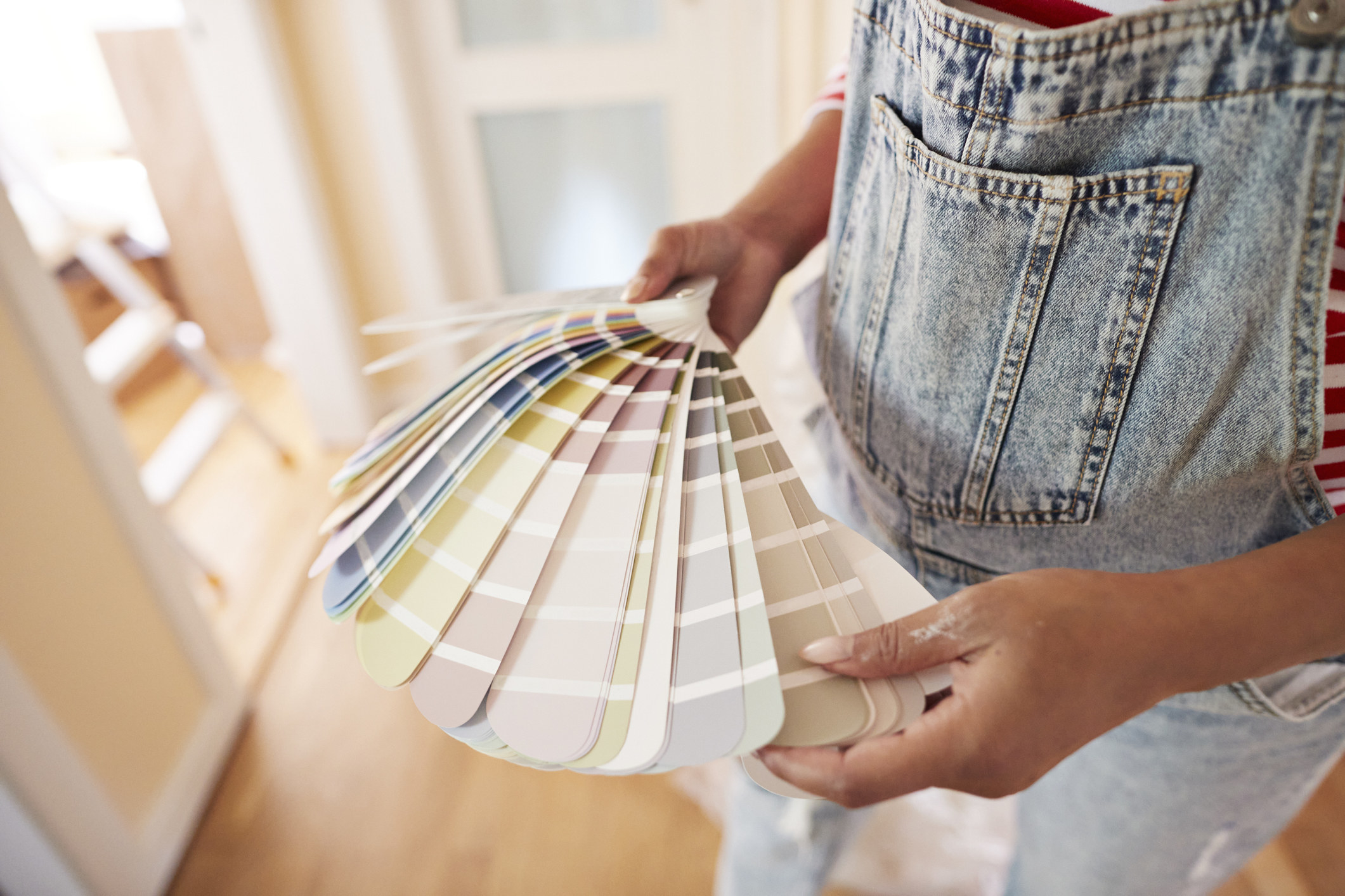 A pregnant woman choosing paint color from a swatch at home